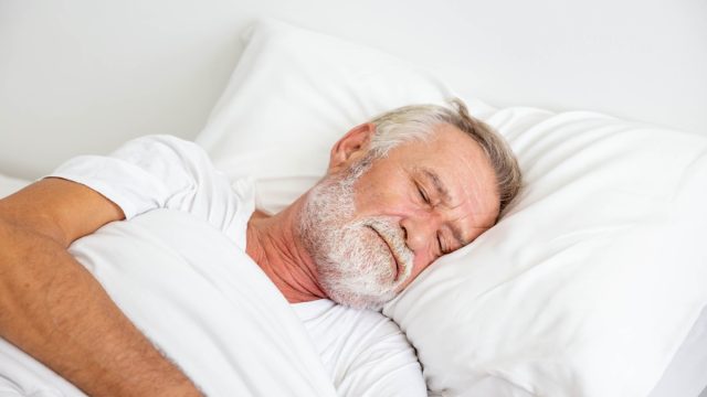 older white man asleep in bed