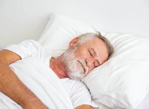 older white man asleep in bed