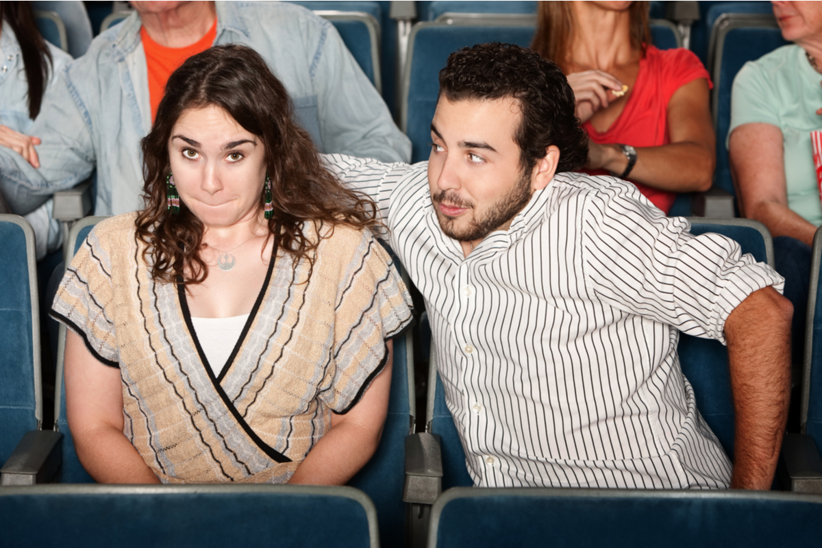 young man trying to hug his date at the movie theater