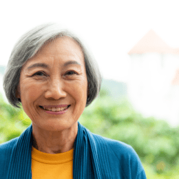 older woman with gray hair smiling outside