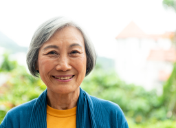 older woman with gray hair smiling outside