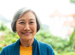 older woman with gray hair smiling outside