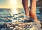 Cận cảnh bàn chân của ai đó khi họ bước xuống nước ở bãi biển