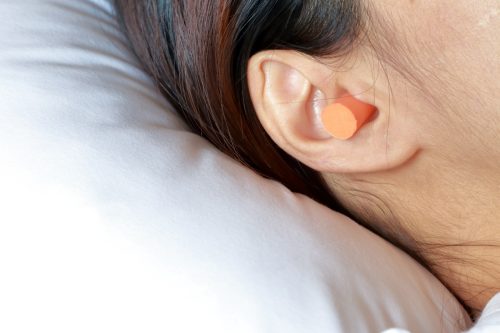 Femeie care doarme cu dopuri de urechi