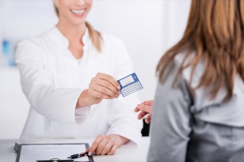 doctor handing health insurance card