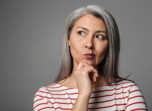 woman over 50 with long hair looking thoughtful