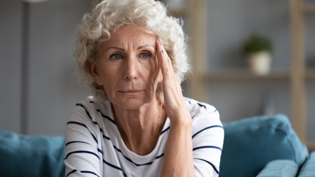 Elderly Woman Holding Her Face and Staring Into the Distance