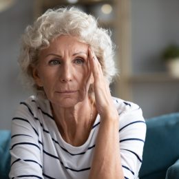 Elderly Woman Holding Her Face and Staring Into the Distance