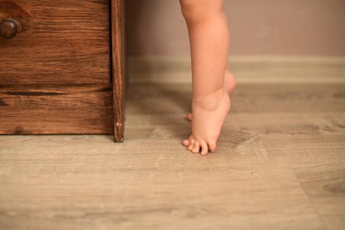 child stanidng on tip toe in front of dresser
