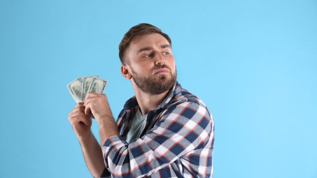 A greedy young man holding a stack of cash