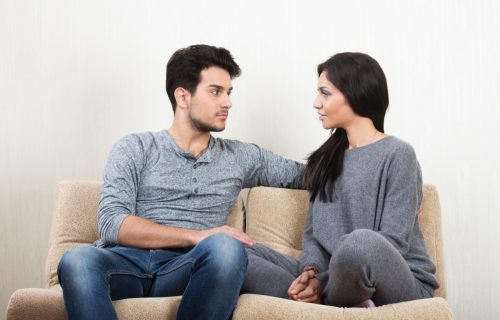 couple talking and sitting on sofa