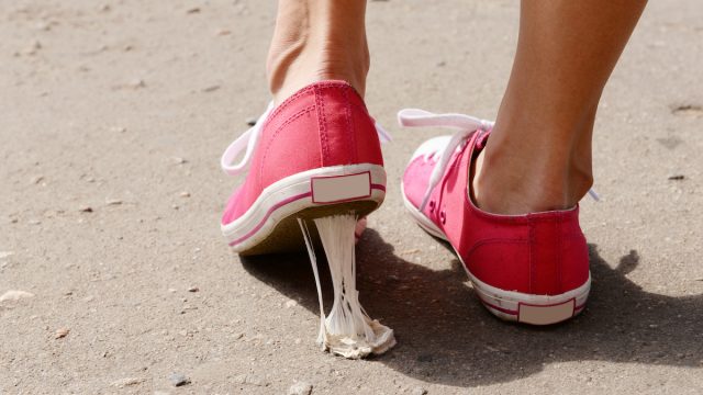 A foot in pink sneakers stuck into chewing gum on street