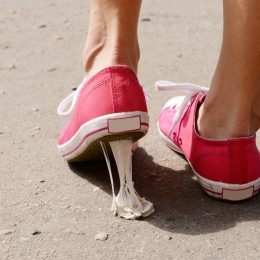 A foot in pink sneakers stuck into chewing gum on street
