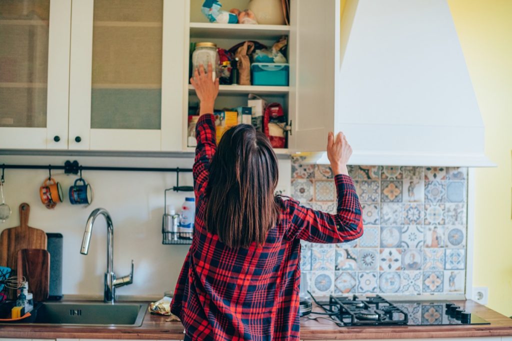 Rear view of a young woman organizing her kitchen at home.