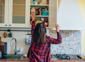 Rear view of a young woman organizing her kitchen at home.
