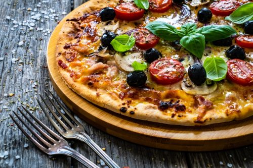 mushroom and olive pizza topped with tomatoes and basil