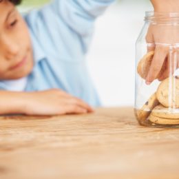 young boy taking a cookie from the cookie jar