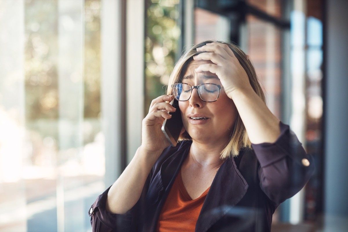 Shot of a young woman looking distraught while talking on a mobile phone in a modern office