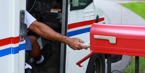 Mail man reaches out of his truck to deliver mail. Official mail delivery slowdown started on October 1, 2021, as seen on October 2, 2021.