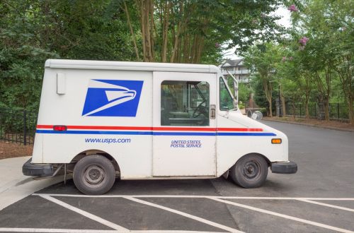 A white, blue and red USPS (United States Postal Service) truck used to deliver mail parked in a residential area in Kennesaw - a city in Cobb County, Georgia, United States