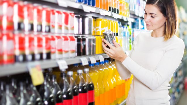 A young woman shopping for soda in a grocery store