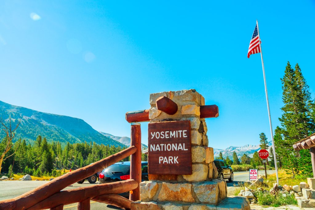The entrance gate of Yosemite National Park with an American flag in the background