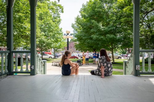 Two young women sitting on the steps of the gazebo in the historic town square of Hammondsport, New York.