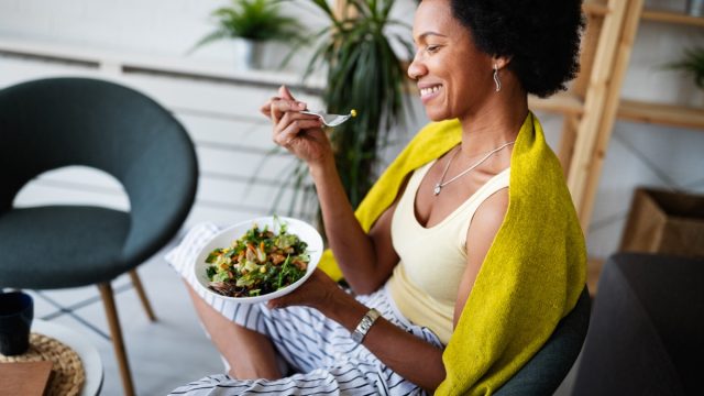 young black woman laughing, eating salad