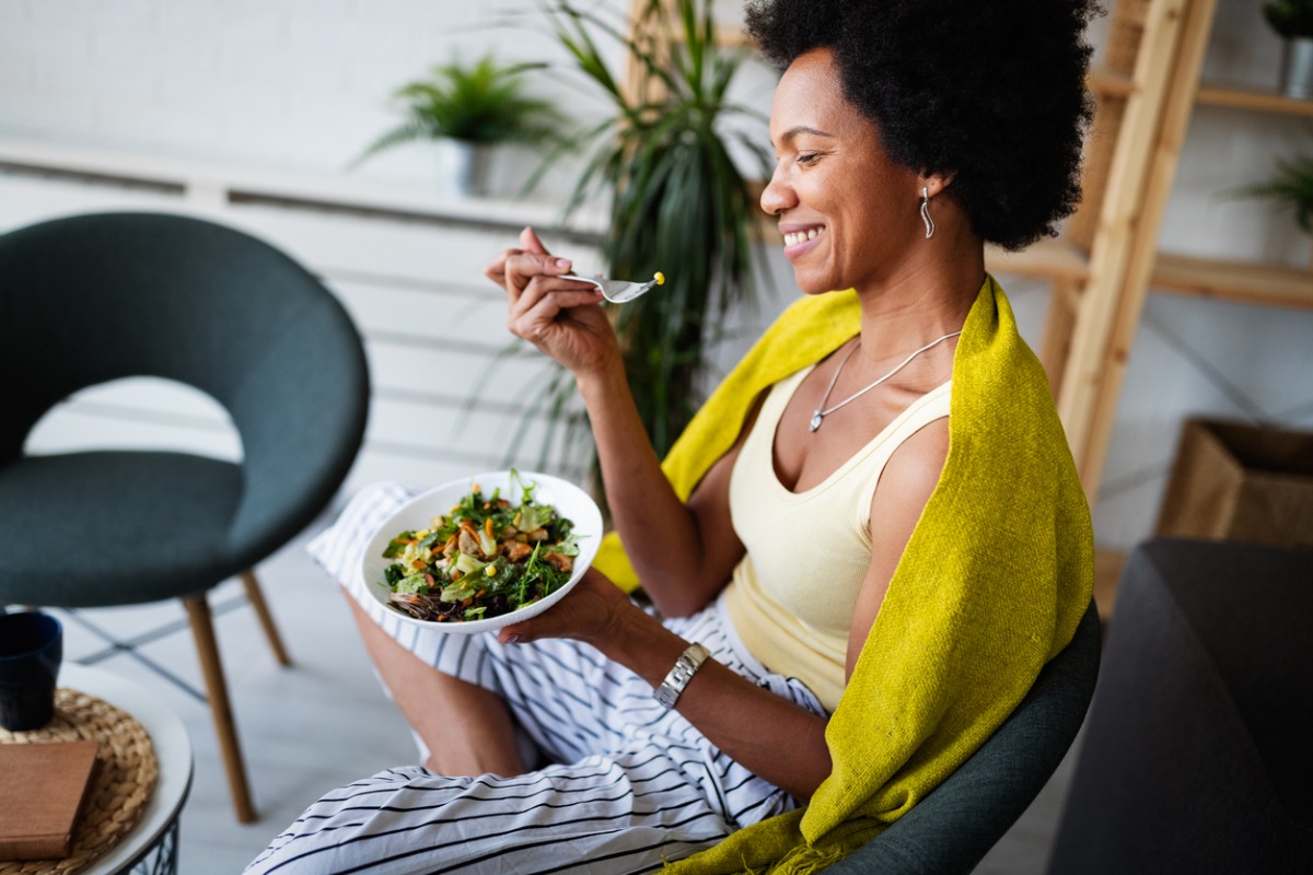 young black woman laughing, eating salad