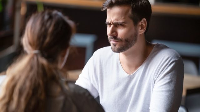 Doubting dissatisfied man looking at woman, bad first date concept, young couple sitting at table in cafe, talking, bad first impression, new acquaintance in public place, unpleasant conversation