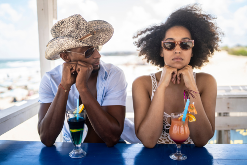 couple bored on vacation drinking cocktails
