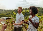A couple enjoying a wine tasting in the middle of a vineyard.
