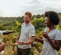 A couple enjoying a wine tasting in the middle of a vineyard.