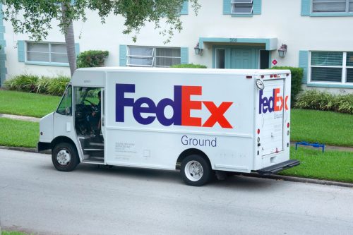 Saint Petersburg, Florida - USA - May 24, 2020 - FedEx truck van parked on side of road to deliver a ground delivery packages to someone who lives in an apartment building with nice landscaping.