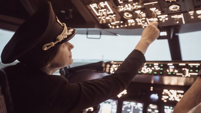 A female pilot in the cockpit of a commercial airliner
