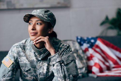 thoughtful african american female soldier in military uniform with american flag on background