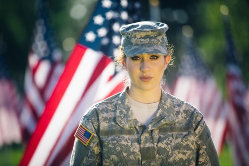 Hispanic American soldier in Uniform standing in front of American flags