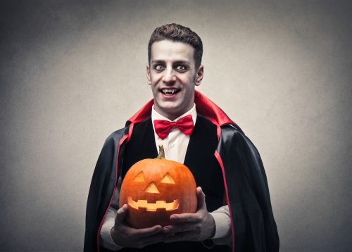 Glume de Halloween - Un bărbat îmbrăcat ca vampir ține în mână un cric sau o lanternă