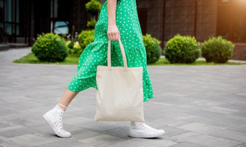 Người phụ nữ trẻ đẹp với túi sinh thái bằng vải lanh trên nền thành phố