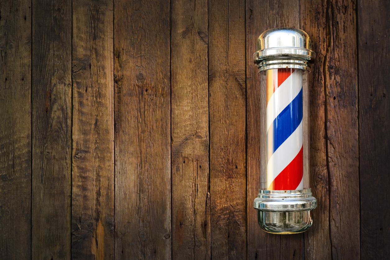 Barbershop pole on a wooden background.