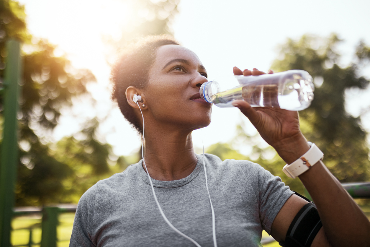 Woman drinking water outside during exercise.