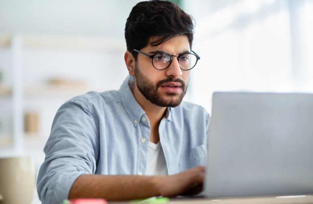 Man wearing glasses looking at laptop concerned