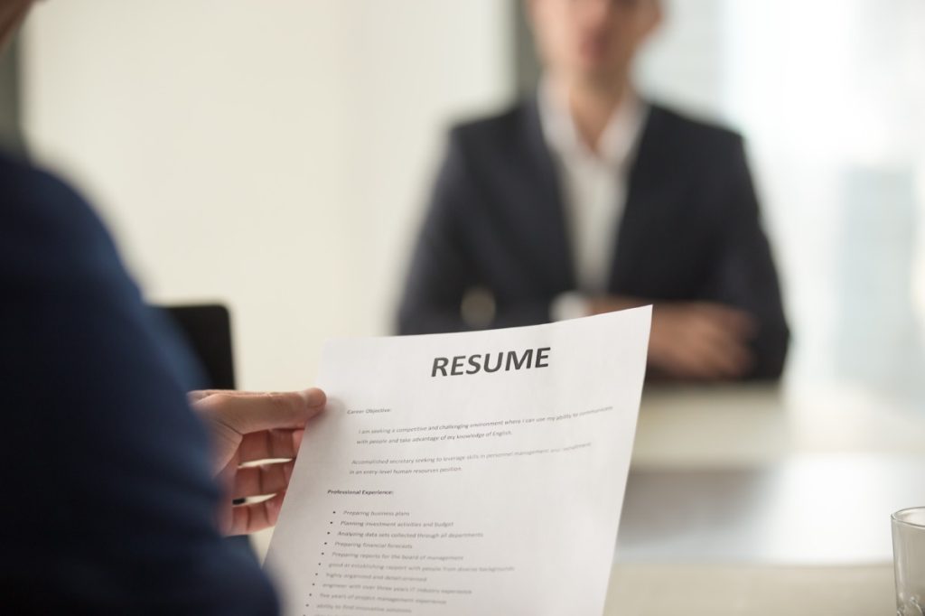 Close up of hiring manager looking at candidate's resume during interview