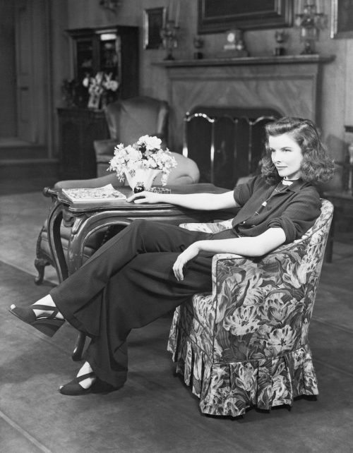 Katharine Hepburn sitting on a chair wearing an outfit with pants in 1940