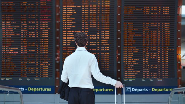 A man looking at the arrivals and departures board in an airport