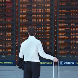 A man looking at the arrivals and departures board in an airport