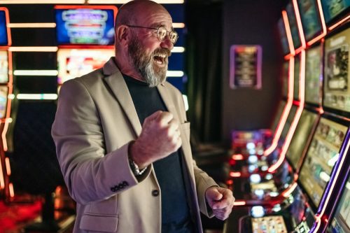 Elderly men using slot machine to gamble in night club, get lucky