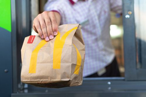 McDonalds worker holding bag of fast food.