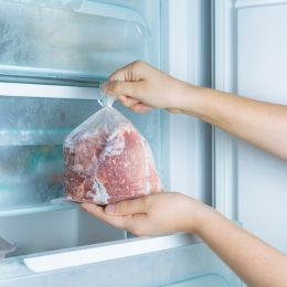 A person taking frozen meat out of the freezer