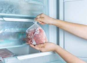 A person taking frozen meat out of the freezer